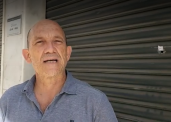 El edil de OSP, Manuel Osorio, junto a una persiana de un local de San Pedro con un impacto de bala.